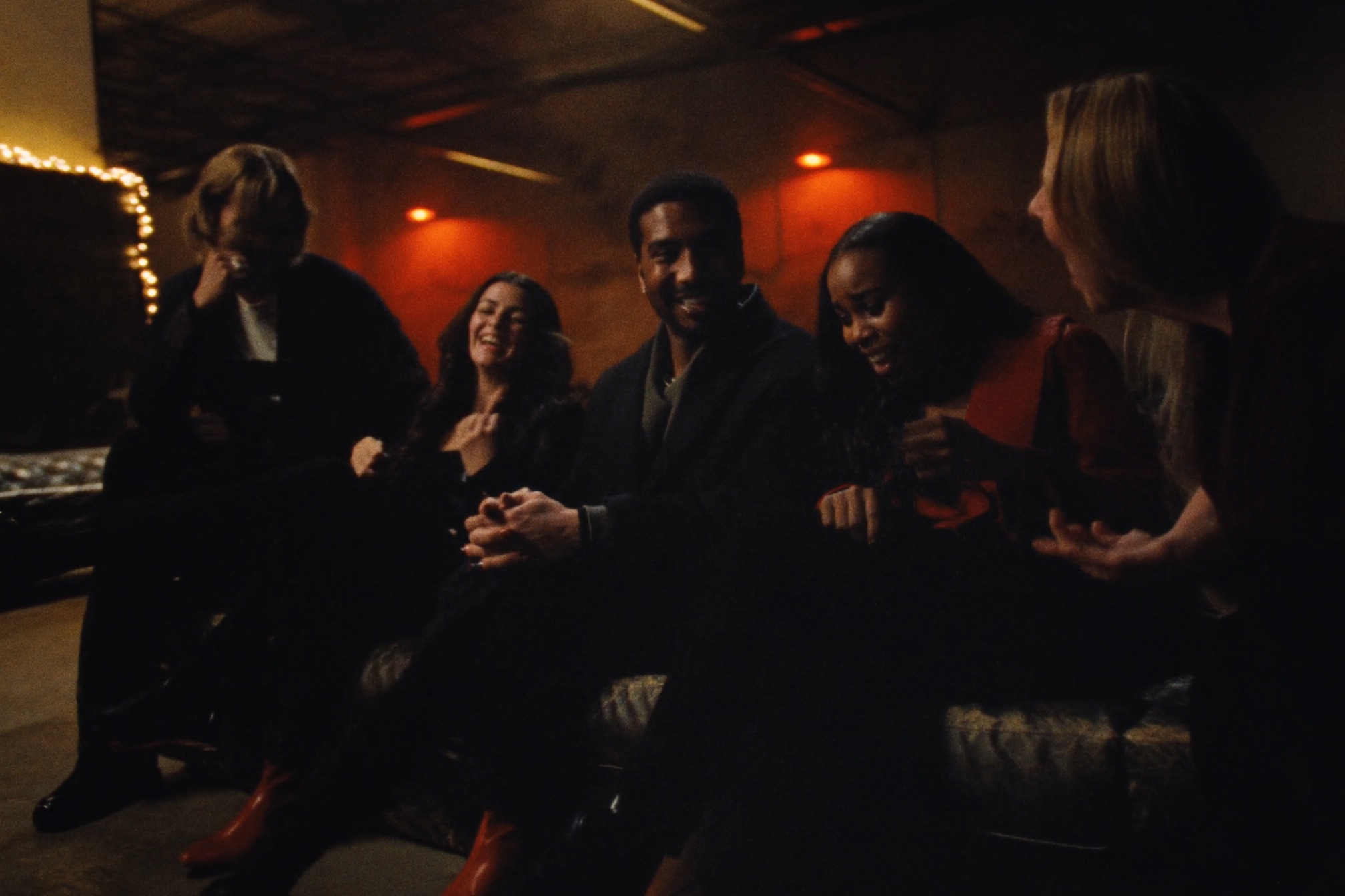 A small group of friends laughing together in a warmly lit industrial loft