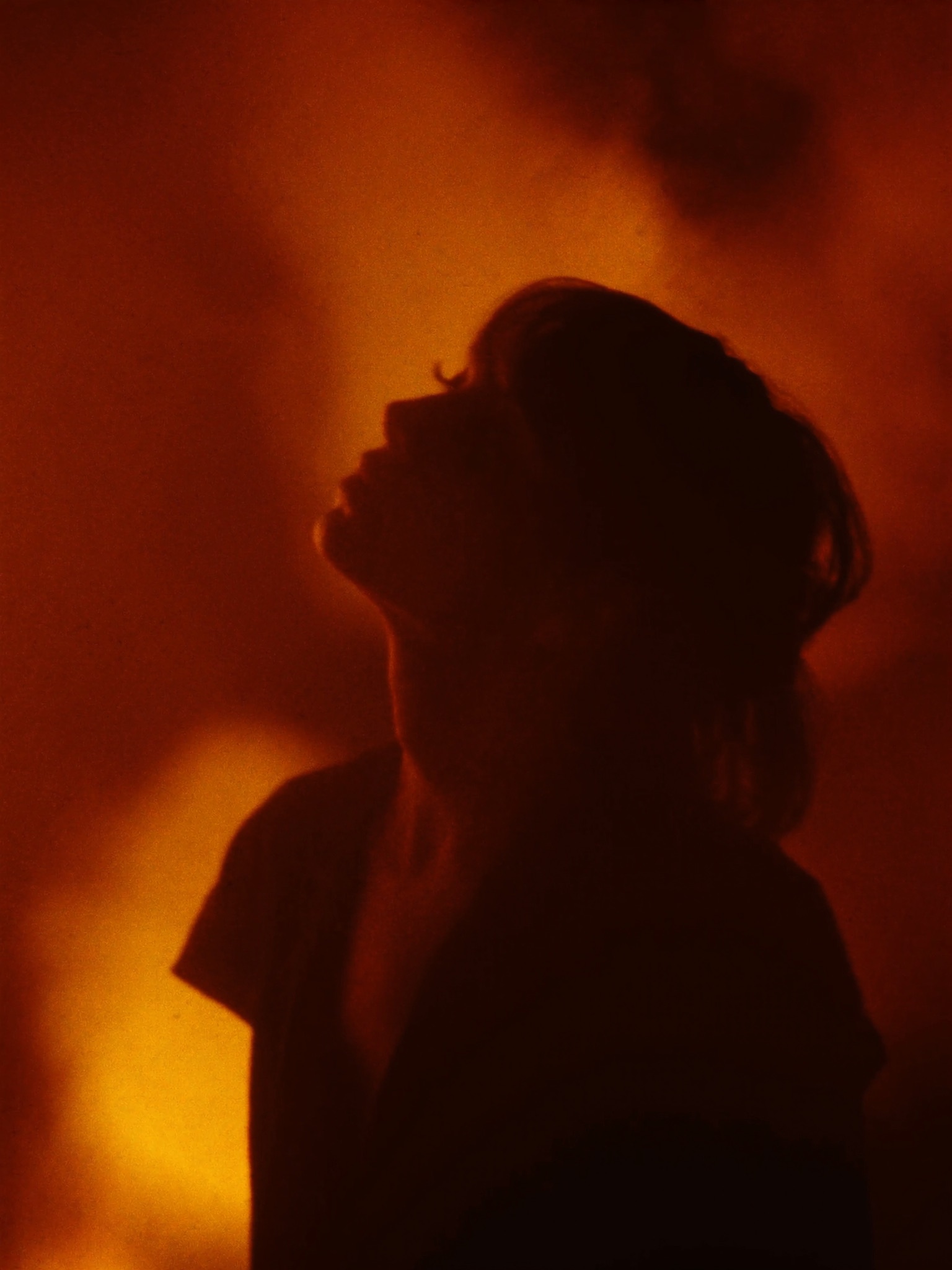 A single figure in silhouette, backlit by warm ember-orange glow